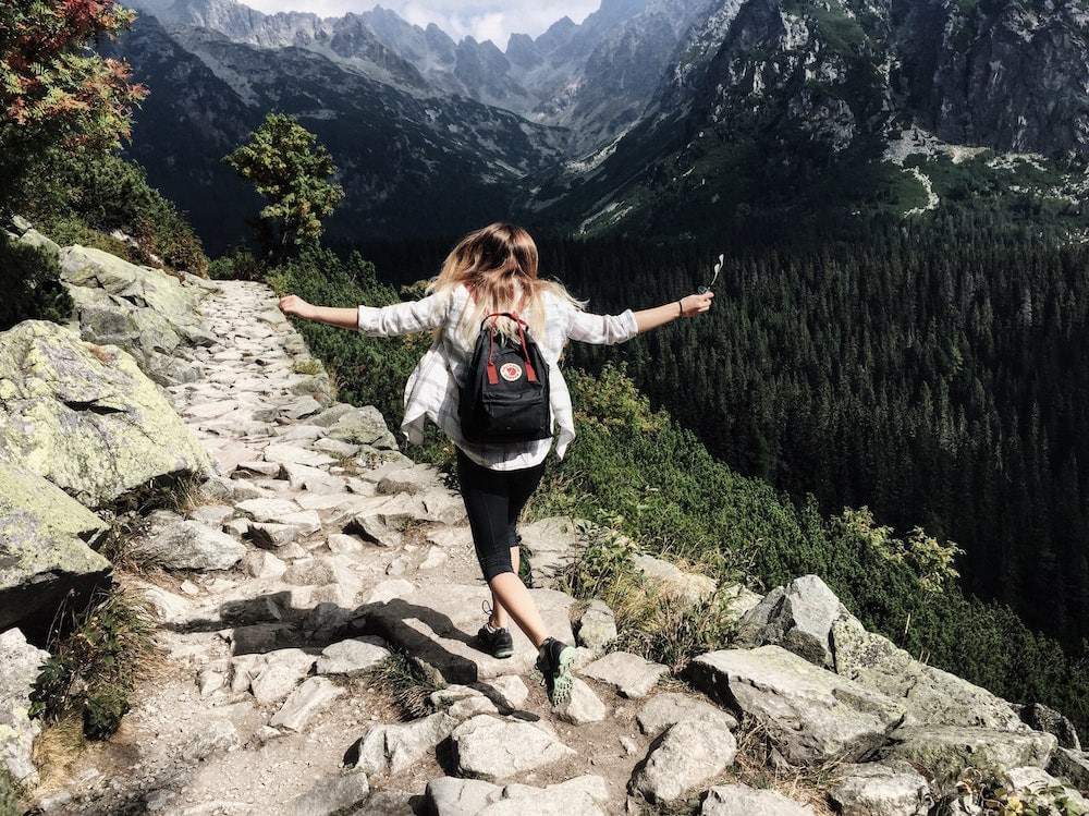 Backpackerin wandert in Australien durch die Berge und ist froh, dass sie eine Krankenversicherung hat.