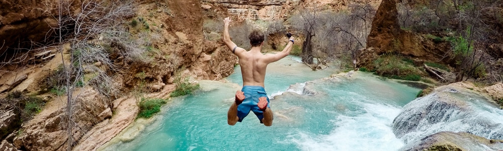 Mann springt von einer Klippe ins Wasser in Australien