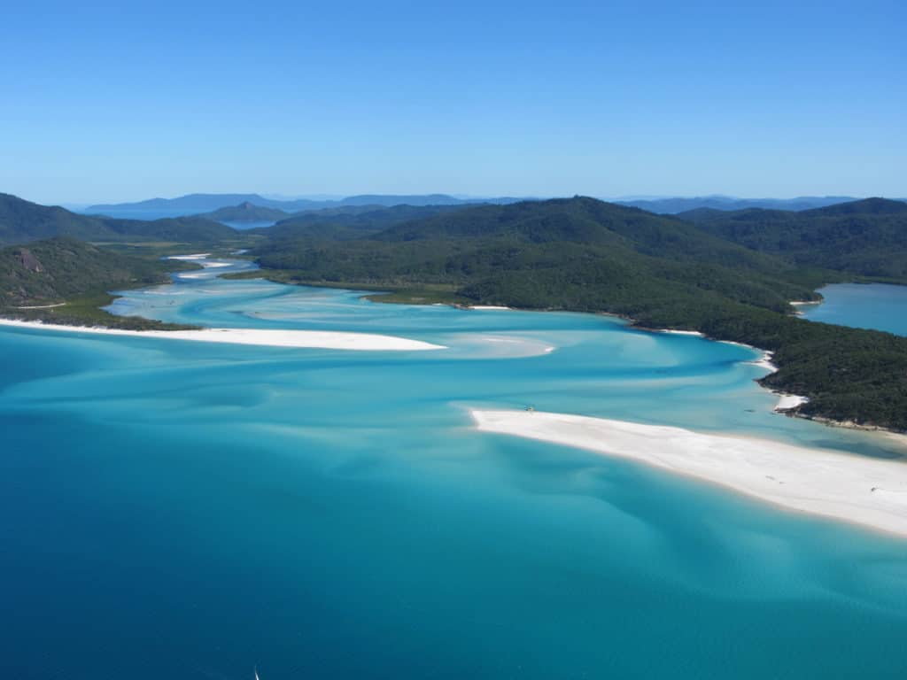 Weißer Sandstrand mit türkisfarbenem Wasser aus der Vogelperspektive auf den Whitsunday Islands in Australien