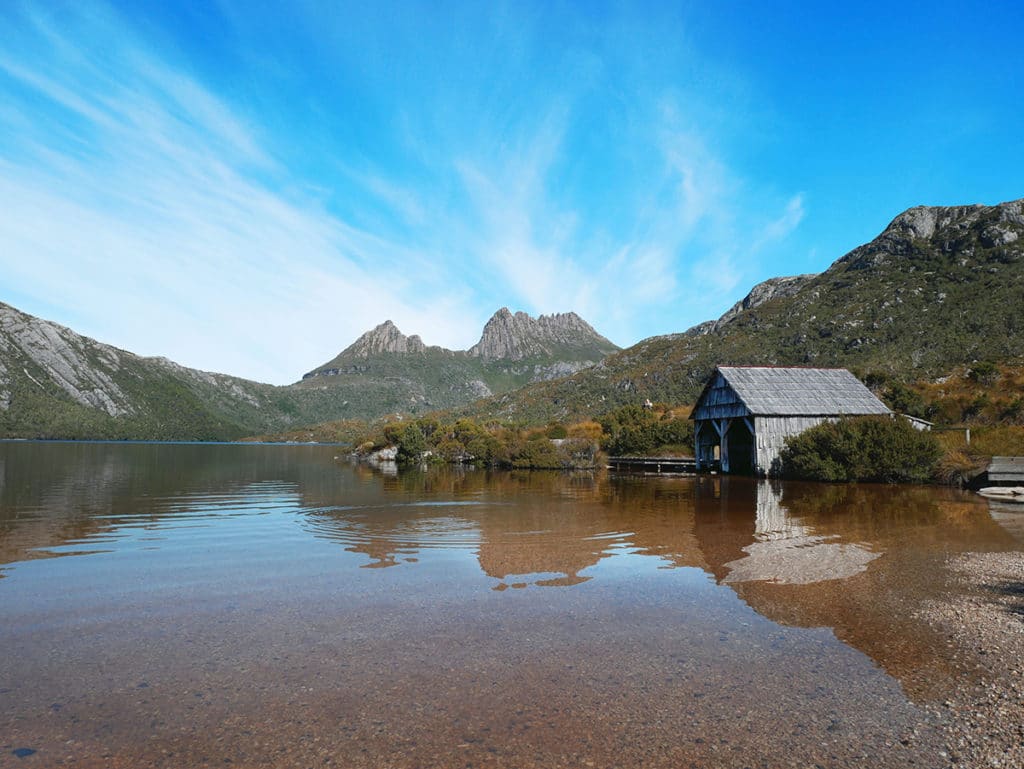 Hütte an einem See mit Bergen im Hintergrund im Cradle National Park