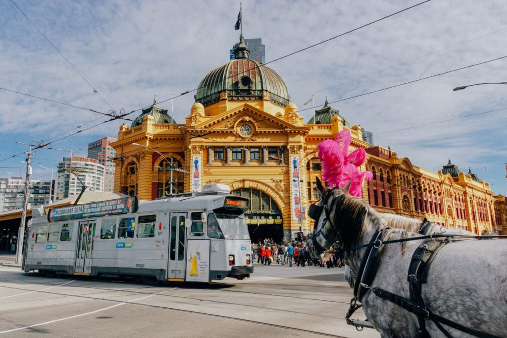 Bahnhof Flinders Station mit einer Straßenbahn und einem Pferd, das daran vorbeigeht